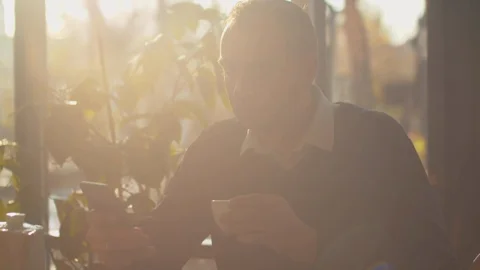 Man drinks tea with phone in hand in a cafe Stock Footage 120723418