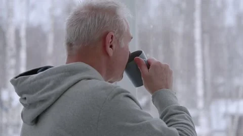 A man drinks tea standing by the window Stock Footage 166932195