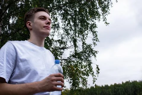 A man drinks water after jogging. Portrait Of Athletic Man in Sportswear Foto stock