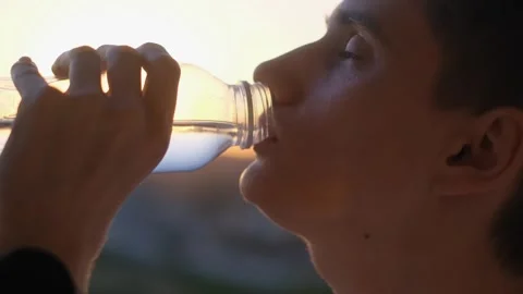 A man drinks water from a bottle at sunset on a hot day Stock Footage 277945111