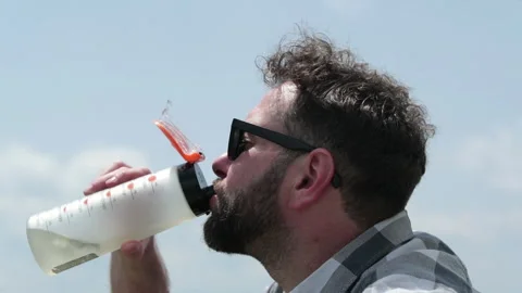 A man drinks water from a bottle while sitting on a rocky slope. Stock-Footage 249215858