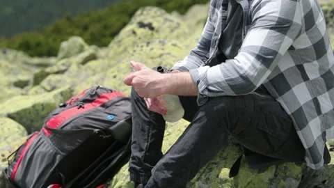 A man drinks water from a bottle while sitting on a rocky slope. Stock Footage 249215922