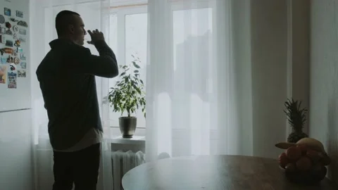 A man drinks water in the kitchen and thinks about something Stock Footage 151690932