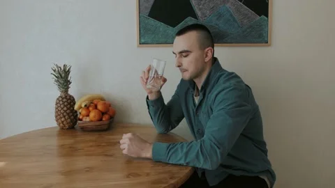 A man drinks water in the kitchen and thinks about something Stock Footage 151690979