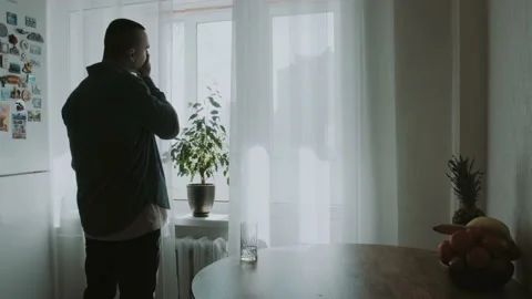 A man drinks water in the kitchen and thinks about something Stock Footage 151690993