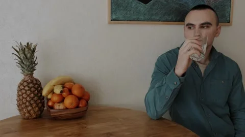 A man drinks water in the kitchen and thinks about something Stock Footage 151691059