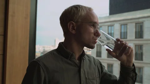 Man drinks water on a skyscraper background, bottom view. Video stock 129195923