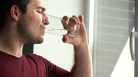 Man drinks water standing by the window in the morning in the room Stock Footage 158684632