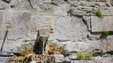 Man drinks water from the tap in an old stone wall. City Rupit, Spain Stock Footage 65222960