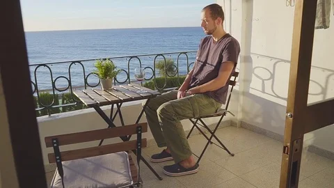 A man drinks wine on a balcony against the sea Stock Footage 85346876