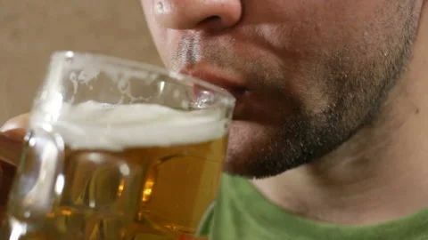 A man drinks a yellow foam drink from a glass glass, it is delicious, he licks h Video stock 93208513