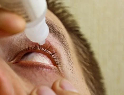 A man drips open human eye with bright red arteries drops to improve vision c Stock Photos