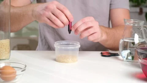 A man drips red dye into a container of rice. An unusual way of coloring and Stock Footage 236920521