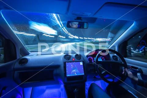 The man drive a car with a gps in a city. Evening night time. Left side traff Stock Photos