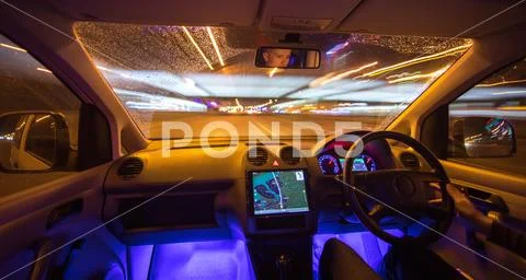 The man drive car in the rain city. Left side traffic. Evening night time Stock Photos