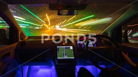 The man drive car in the rainy city. Left side traffic. Evening night time Stock Photos