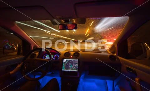 The man drive with a map on the rainy road. Evening night time. Inside view Stock Photos