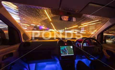 The man drive with navigation in the night city. Left side traffic. Wide angl Stock Photos