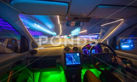 The man drive a vehicle on the night road. Inside view. Left side traffic Stock Photos