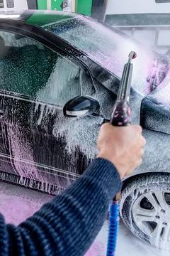 Man Driver Applying Pink Foam To Black auto Wash At Car Wash For Vehicle Care Stock-Fotos