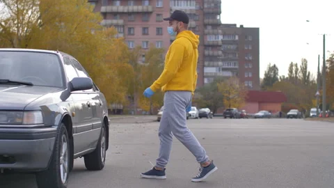 A man, a driver in disposable gloves and a medical mask, opens the driver's seat Stock Footage 163183572