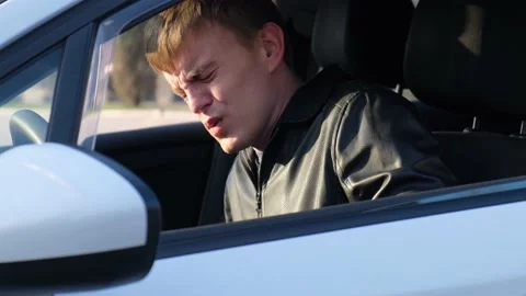 A man driver experiences pain and discomfort when getting into a car 動画素材 152579667