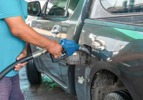 Man driver hand refilling and pumping diesel oil the car. Stock Photos