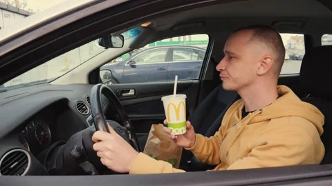 Man driver sit in a car hold drink a cup of coca cola from mcdrive - sweet carbo Stock Footage 142632554