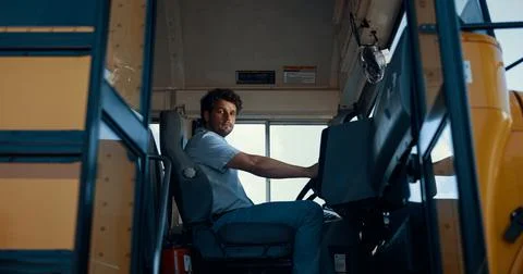 Man driver sitting schoolbus cabin alone. Young chauffeur opening vehicle door. Stock Photos