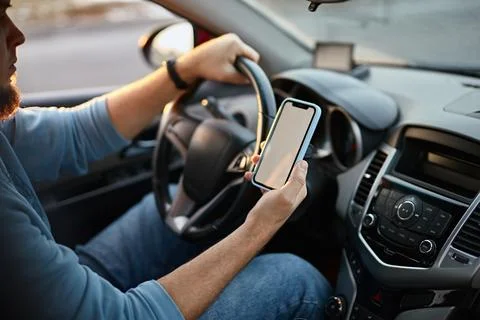 Man driver using mobile phone screen blank mockup on the road while driving a Foto stock
