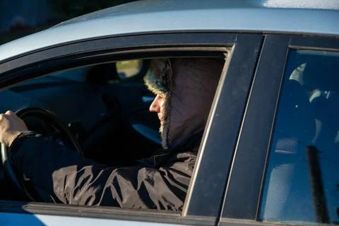 Man driver in winter hat driving car. Delivery worker during cold season Stock-Fotos