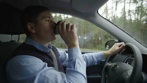 A man drives a car and drinks coffee Stock Footage 236928895