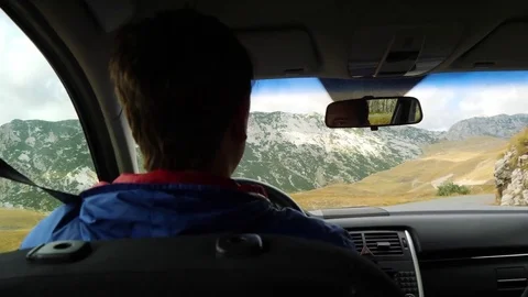 Man drives a car in sharp turn of mountain road with a view on rocky ridge of Stockbeeldmateriaal 83123871