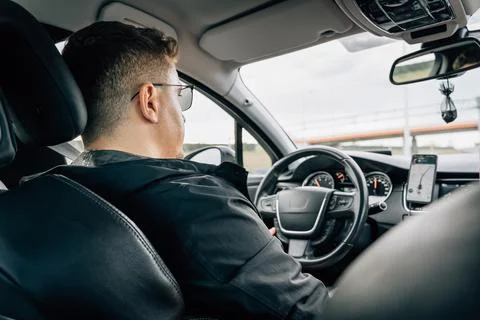 A man drives a car using a navigation application installed on a smartphone Stock Photos