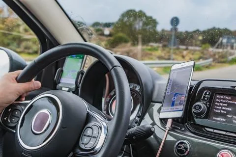 A man drives a car using two navigators for the route Stock Photos