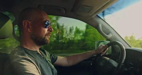 Man drives the car while sunset.  Adult  bearded man driving the car.  Young Stock Footage 131041806