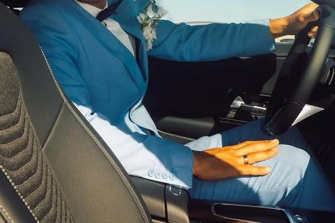 Man drives car while wearing a blue suit and holding the steering wheel with  库存照片