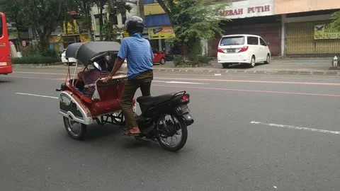 A man drives a motorized rickshaw on the streets of Surakarta Stock Footage 270074886