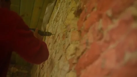 A man drives nails into a brick wall Stock Footage 131339644