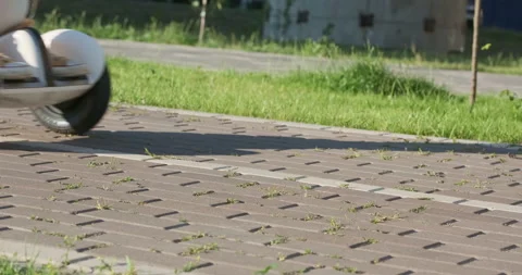 Man drives past on electric hoverboard, gyroscooter on sidewalk. Close-up, side Stock Footage 247175461
