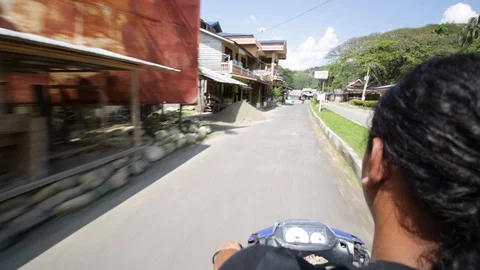 Man drives through rural town in Indonesia on a sunny day Stock Footage 107635641