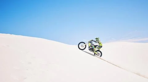 Man, driving and motorbike on sand with blue sky or sport, adventure and outdoor Stock Photos