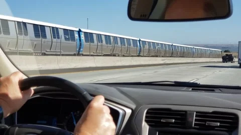 Man driving beside BART train that is heading toward Antioch. Stock Footage 325738592