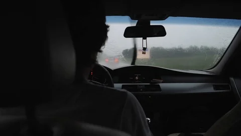 Man driving a car in the rain in the windshield dripping water Stock Footage 111698616