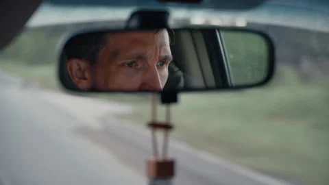 Man driving a car reflected in rearview mirror Stock Footage 328558009
