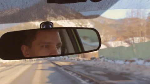 Man is driving a car. Reflection face in rearview mirror. Sunset sunrise time Stock-Footage 74433936