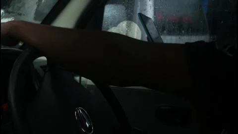 A man is driving a car while playing on his cellphone when it rains. Stock Footage 266683163