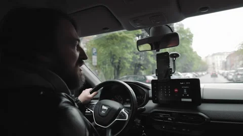 Man driving car while using hands-free phone. A man in a leather jacket drives a Stock Footage 278745937