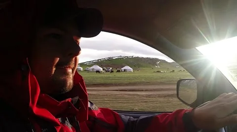 Man is Driving in Highland Passing by Several Yurts Stock Footage 60583275