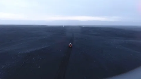 Man driving a quad to a wrecked plane on black dirt Icelandic beach Video stock 100031969